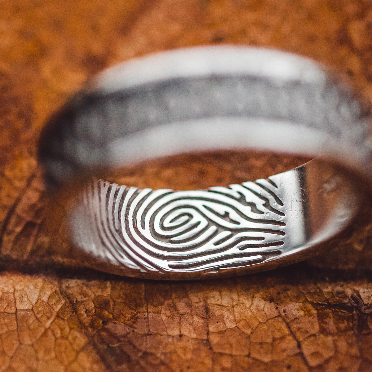 Wedding rings with fingerprints close-up on wet brown autumn leaf skeleton texture